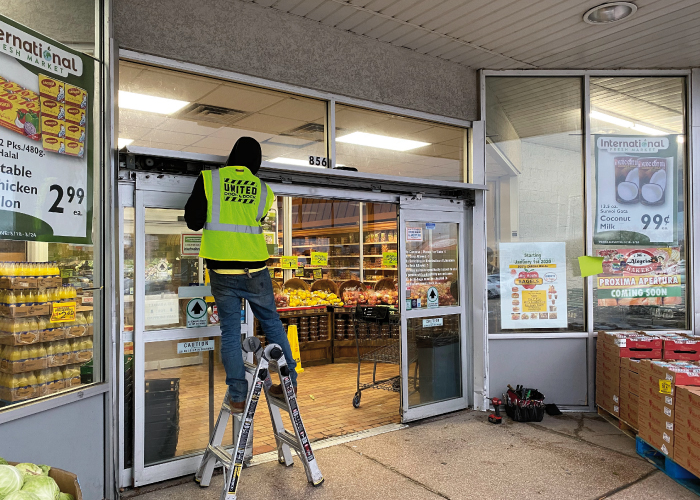 United Door and Dock Crew Member Servicing Automatic Grocery Store Glass Doors