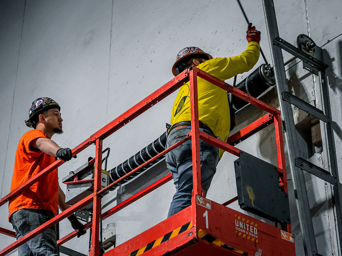 United Door and Dock Crew Members Working on Commercial Overhead Door Springs